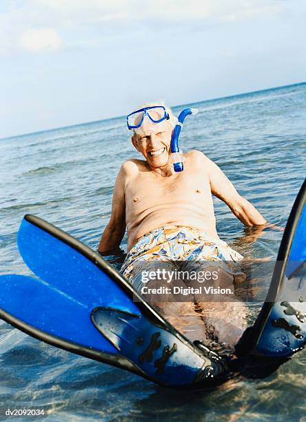 portrait of a senior man in a scuba mask and swimming flippers lying in the sea - old people diving stock pictures, royalty-free photos & images