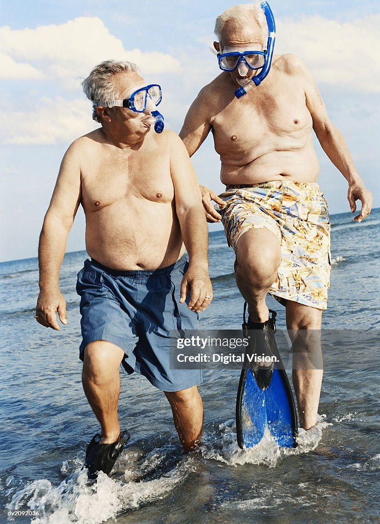 Two Senior Men in Scuba Masks and Flippers Wading in the Sea