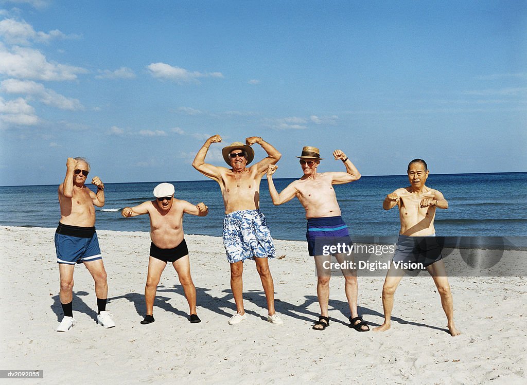 Five Senior Men in Swimming Trunks Stand on the Beach Flexing Their Muscles