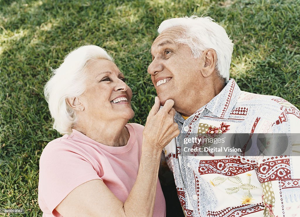 Senior Couple Lie on the Grass, Embracing