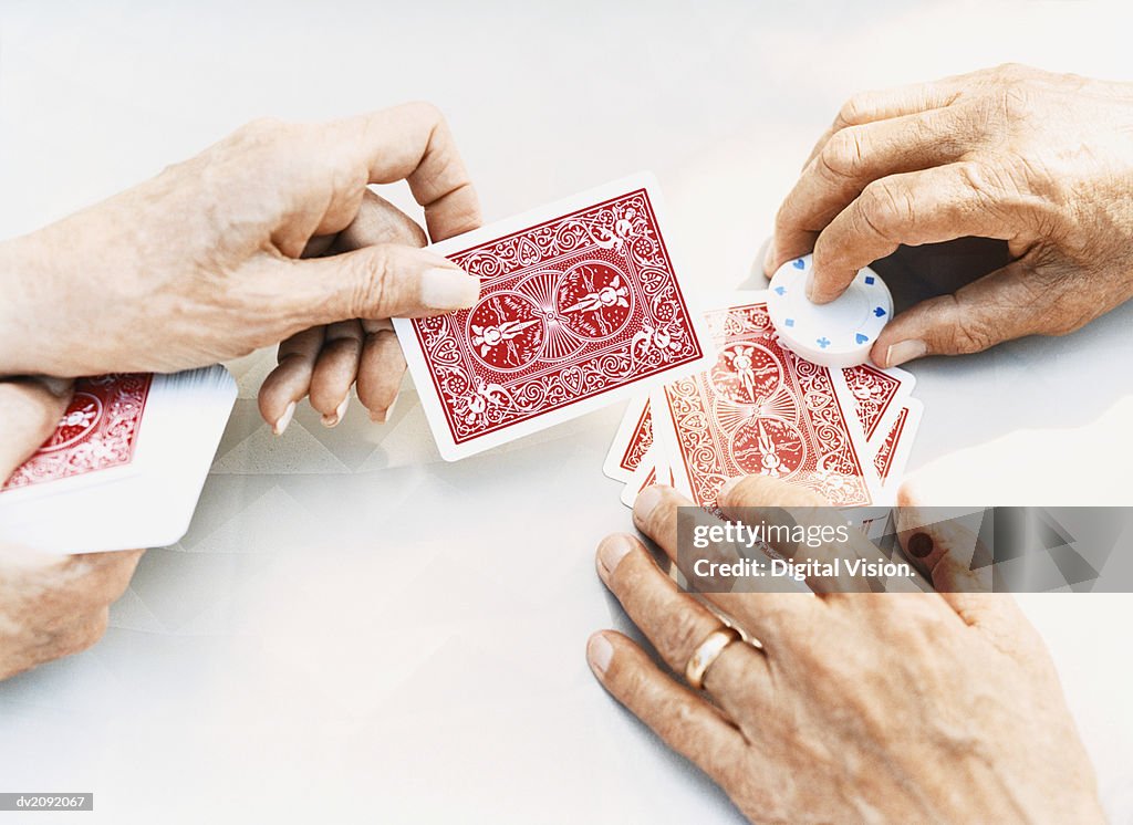 Close-Up on the Hands of a Senior Man and Woman Holding Playing Cards and Gambling Chips