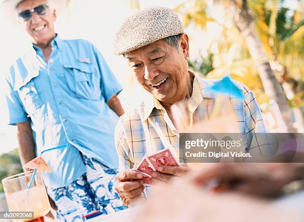 smiling holding a set of playing cards - senior men playing cards stock pictures, royalty-free photos & images