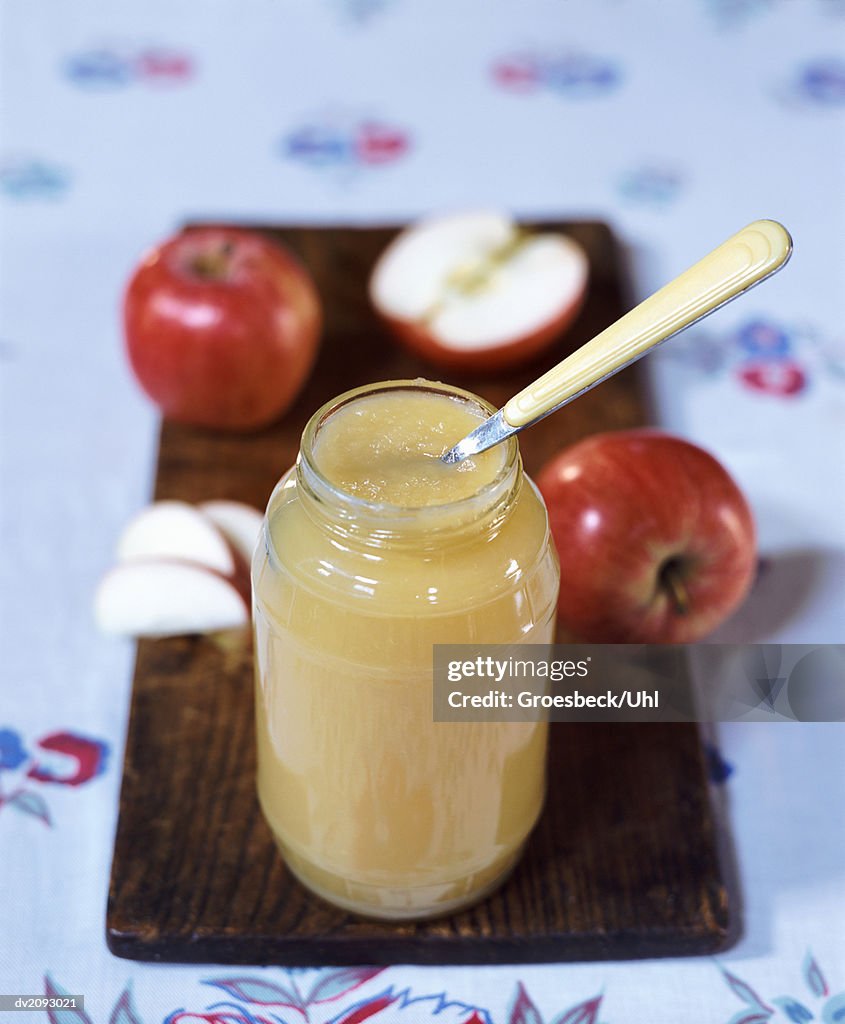 Jar of Apple sauce With Spoon on a Wooden Dish