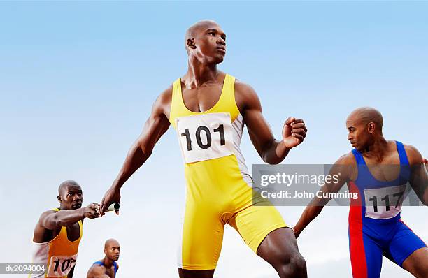relay runners passing batons to team mates - sports competition format stock pictures, royalty-free photos & images