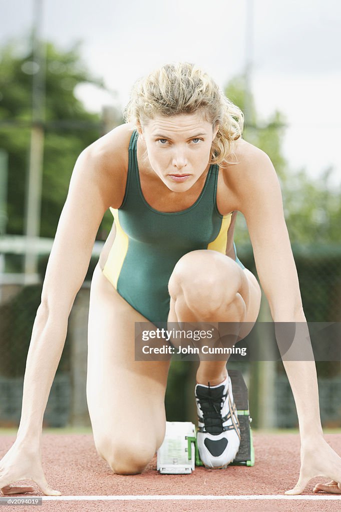 Female Athlete Crouching on the Starting Blocks of a Running Track