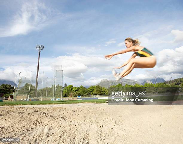 woman doing the long jump - womens field event stockfoto's en -beelden
