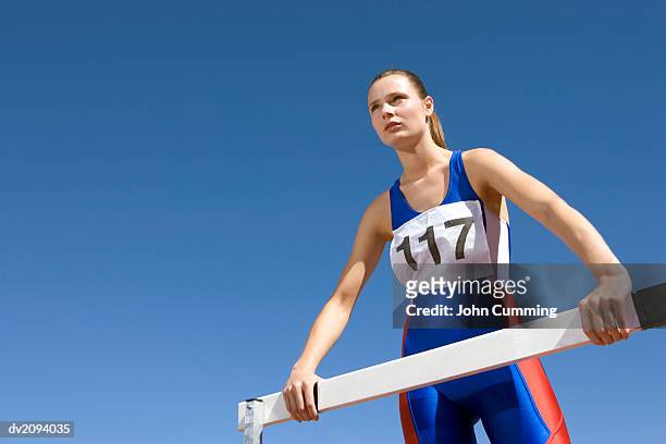 low angle shot of a determined female athlete standing by a hurdle - pettorina foto e immagini stock