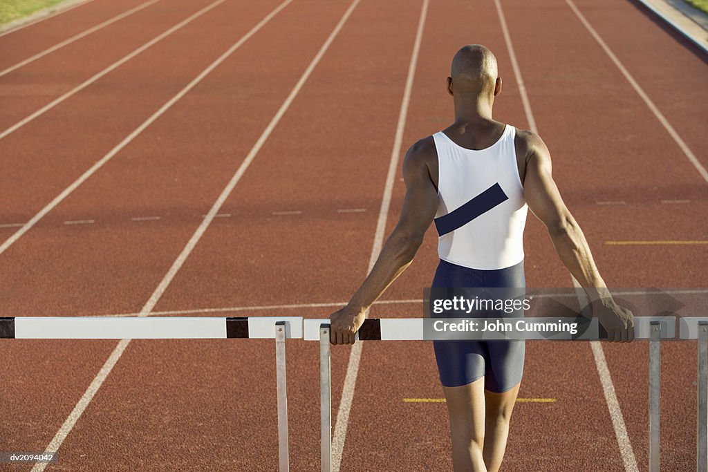 Rear View of an Athlete Standing in Front of a Hurdle on a Track