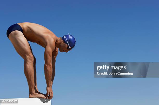 male swimmer about to dive into a swimming pool - young men in speedos stock-fotos und bilder