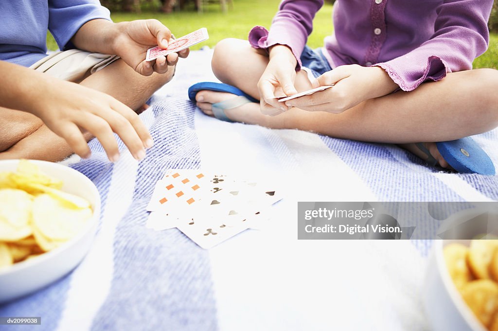 Low Section of a Young Boy and Girl Sitting on a Rug, Playing a Card Game