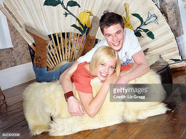 portrait of a young couple lying on a fur rug in their home - liz white stock pictures, royalty-free photos & images