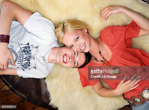 portrait of a young couple lying cheek to cheek on a fur rug - liz white stock pictures, royalty-free photos & images