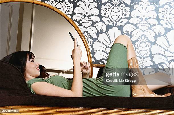 young woman lying on a chaise lounge and looking into a compact mirror - liz white stock pictures, royalty-free photos & images