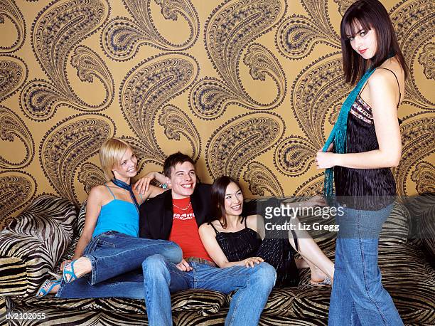 three young people sitting on a zebra print sofa laugh at their friend, showing off - liz white stock pictures, royalty-free photos & images