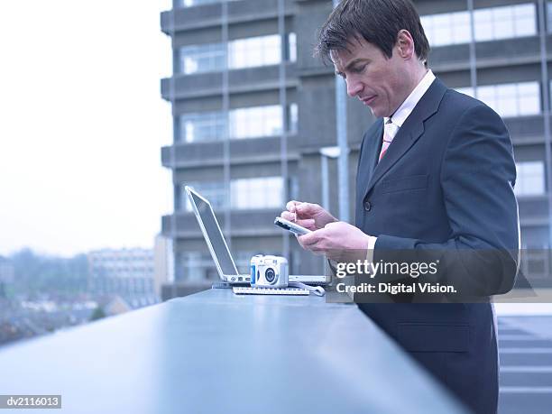 businessman outdoors in the city using a handheld pc - pc foto e immagini stock