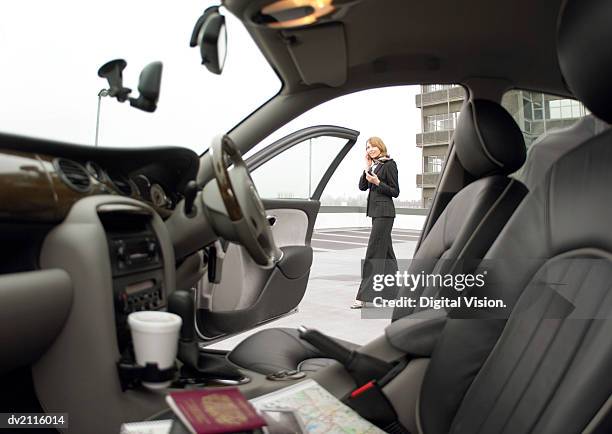 businesswoman standing by her car and using a mobile phone - open car door stock pictures, royalty-free photos & images