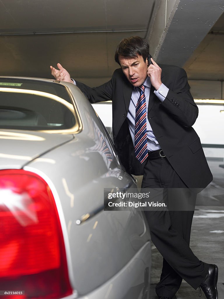 Businessman Standing by His Car and Using His Mobile Phone