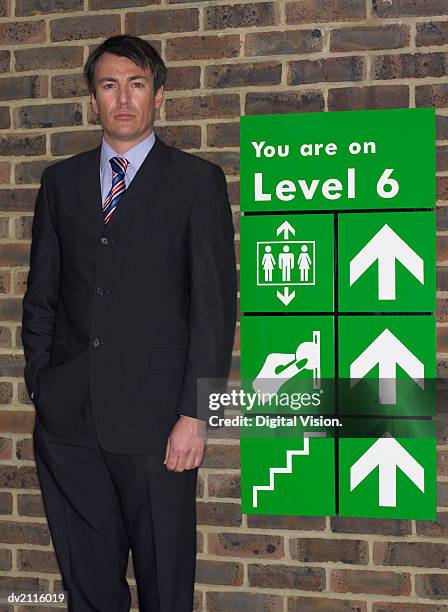 businessman standing by a car park sign - westers schrift stockfoto's en -beelden