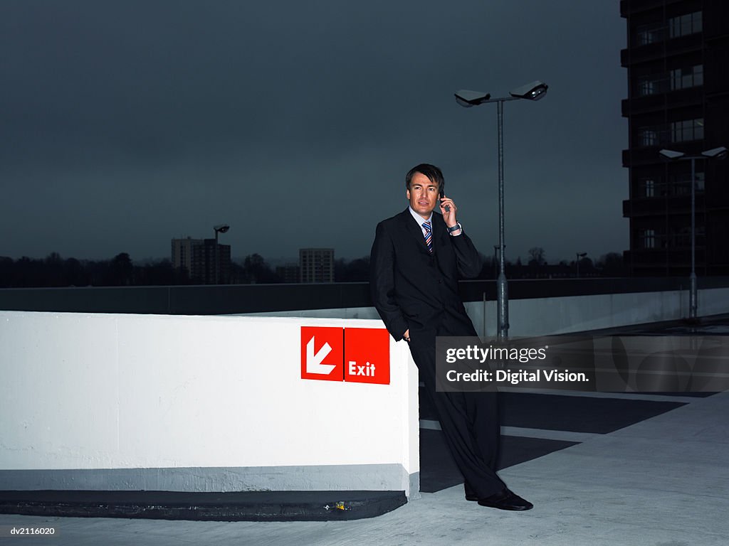 Businessman Using His Mobile Phone in a Car Park at Night