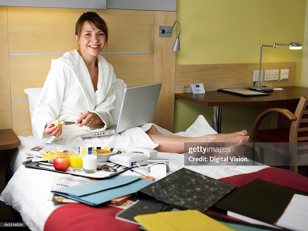 Businesswoman Wearing a Dressing Gown and With a Laptop in a Hotel Room