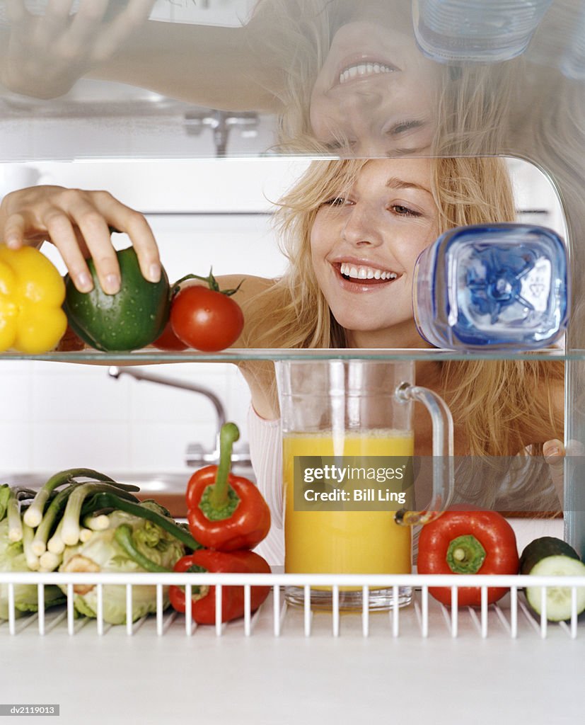 Woman Taking a Green Pepper from a Fridge Rack