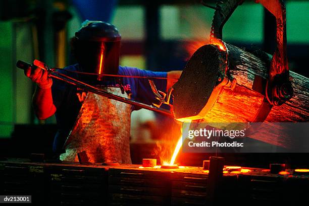 foundry worker pouring steel - smederij stockfoto's en -beelden