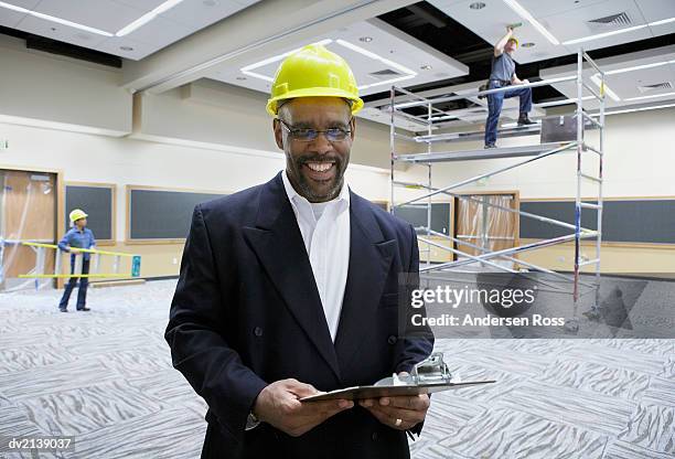 portrait of a smiling man wearing a hard hat and holding a clipboard - clipboard and glasses imagens e fotografias de stock