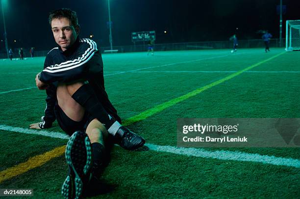 portrait of a man sitting down at the edge of a football pitch - tracksuit jacket bildbanksfoton och bilder