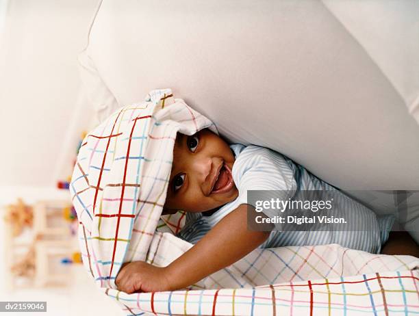 young boy sitting on a chair and playing under a sheet - black toddler boy stock-fotos und bilder