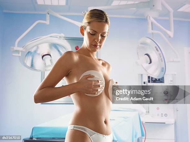 woman holding implants on her breasts - aumento dos seios imagens e fotografias de stock