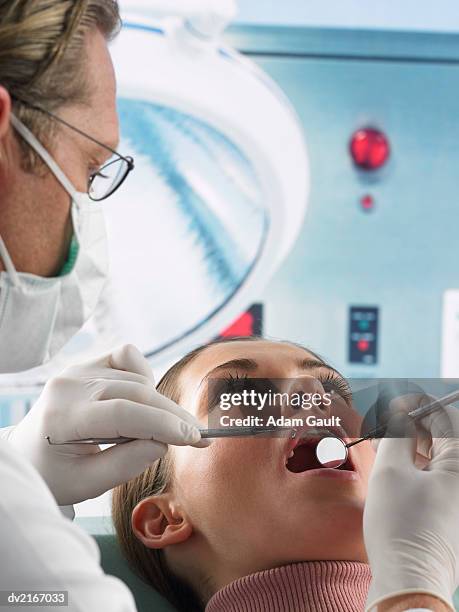 dentist looking at a woman's teeth - rimotore di placca foto e immagini stock