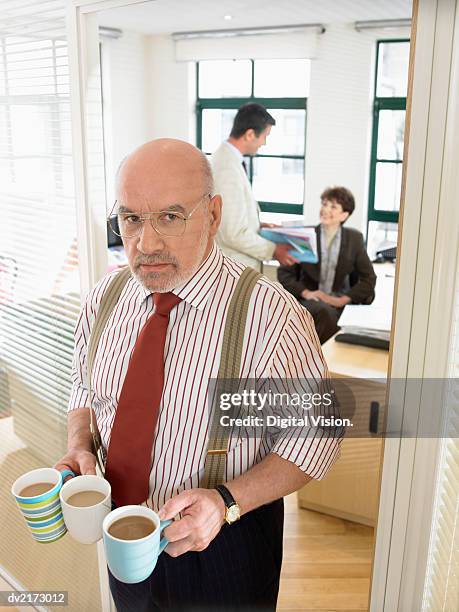 businessman holding two cups of coffee in an office - cross stripes shirt stockfoto's en -beelden