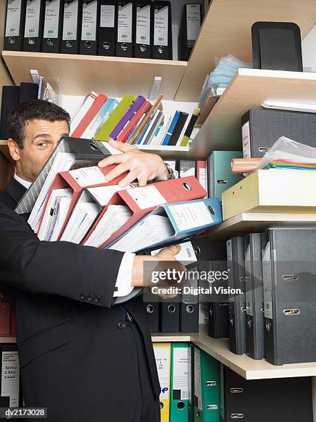 businessman carrying a large pile of ring binders - binders stockfoto's en -beelden