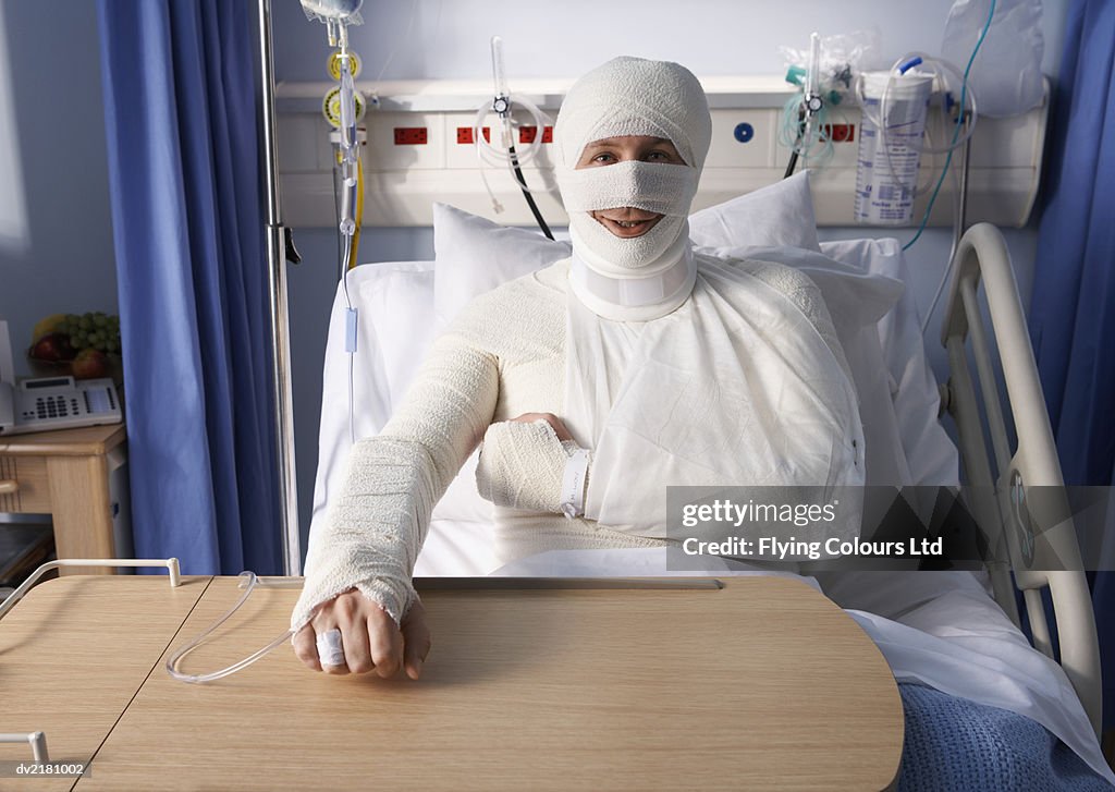 Man Lying in a Hospital Bed, Covered in Bandages
