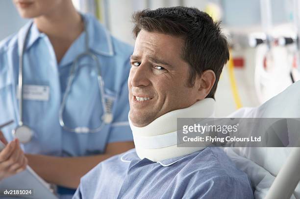 portrait of a man in a hospital bed wearing a neck brace - collarín médico fotografías e imágenes de stock