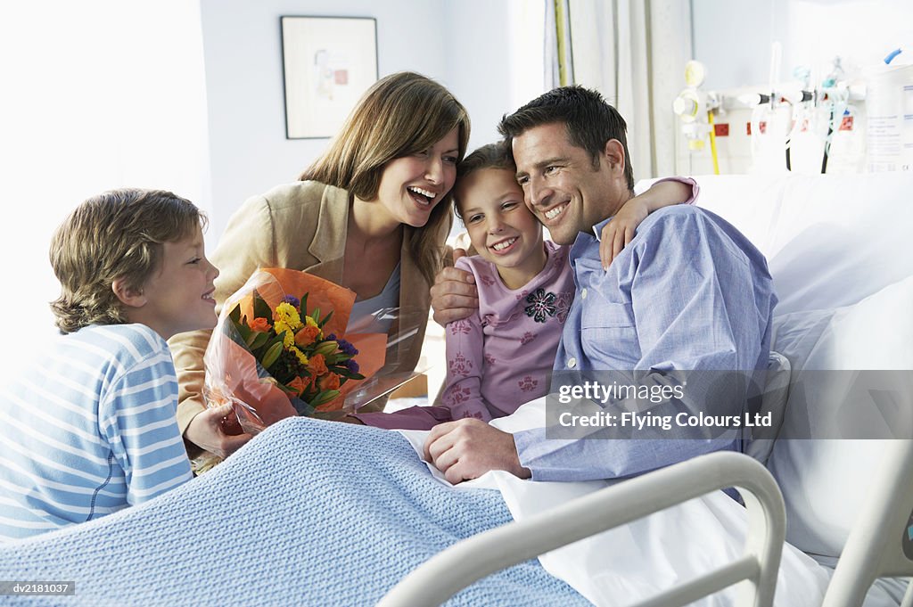 Man Lies in a Hospital Bed With His Family by His Side