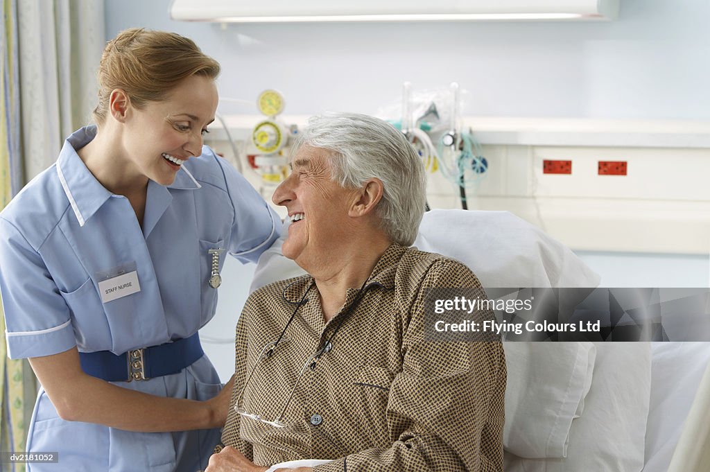 Nurse Smiling at a Senior, Male Patient Lying in Bed