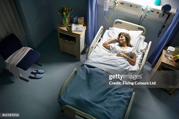 female patient sleeping in a hospital bed at night - brunette woman bed stockfoto's en -beelden