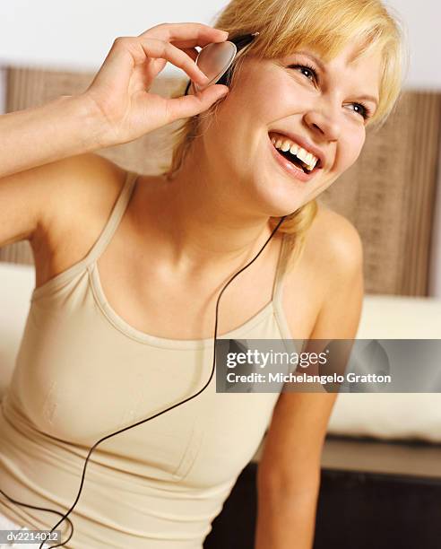 young woman listens to music with headphones, laughing - wonky fringe stock pictures, royalty-free photos & images