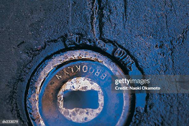 close up of water covering rusted metal circle on black surface - burberry and fox searchlight pictures honour the cast and filmmakers of brooklyn stockfoto's en -beelden