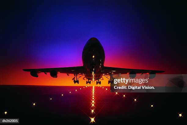 plane lifting off from runway at dusk - airport runway stock pictures, royalty-free photos & images