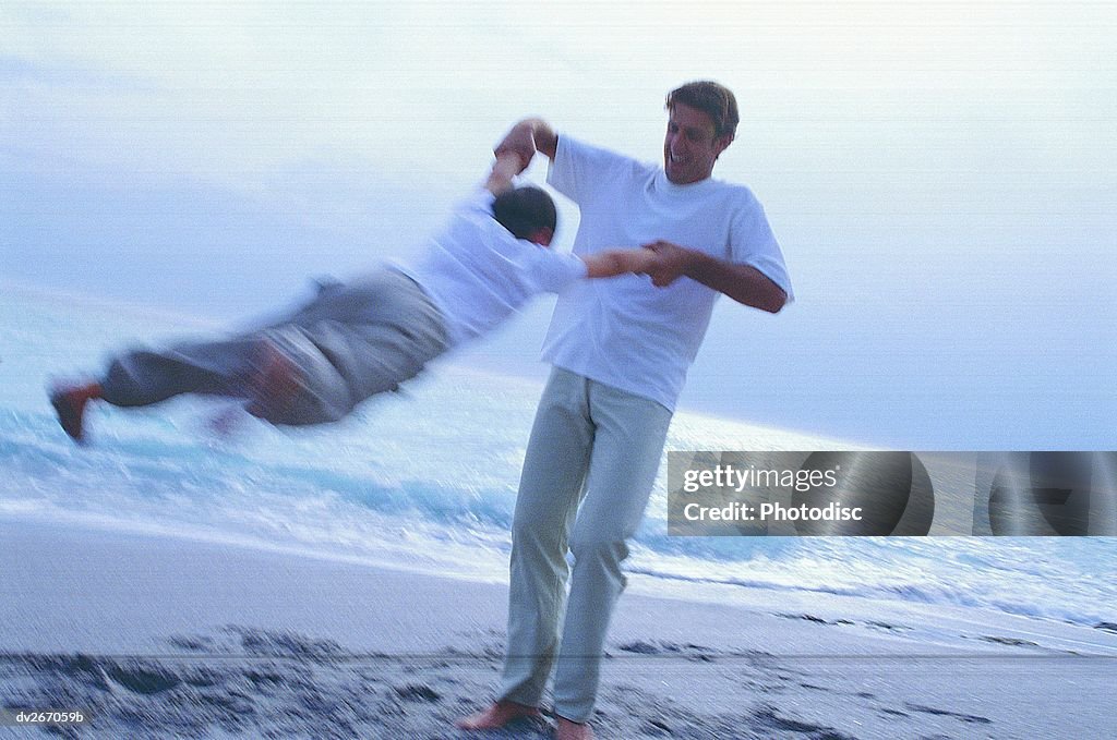 Blurred shot of father & son swinging son around