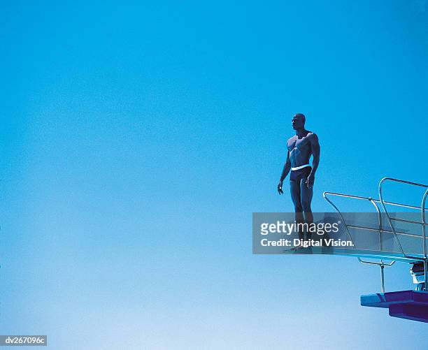 diver perched on edge of diving board - young men in speedos 個照片及圖片檔