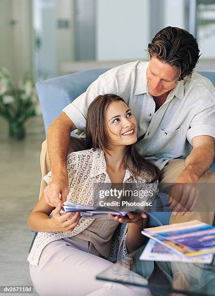 affectionate couple reviewing travel brochures - travel​ stock pictures, royalty-free photos & images