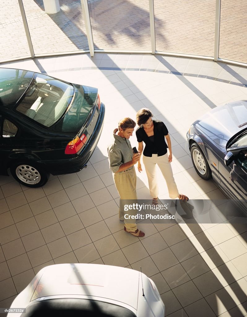 Overhead view of couple looking at cars in showroom
