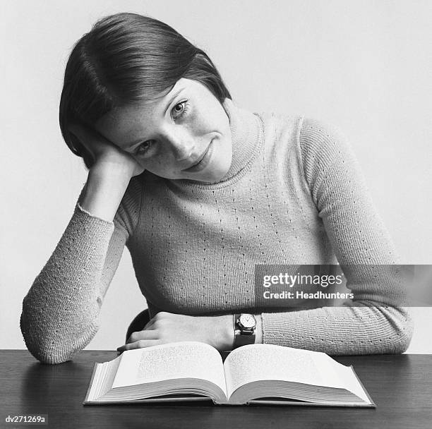 young woman leaning on hand, reading - headhunters stock-fotos und bilder