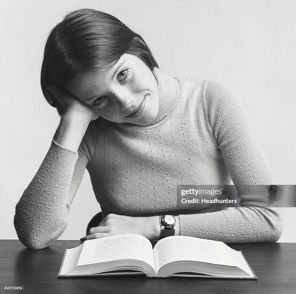 Young woman leaning on hand, reading