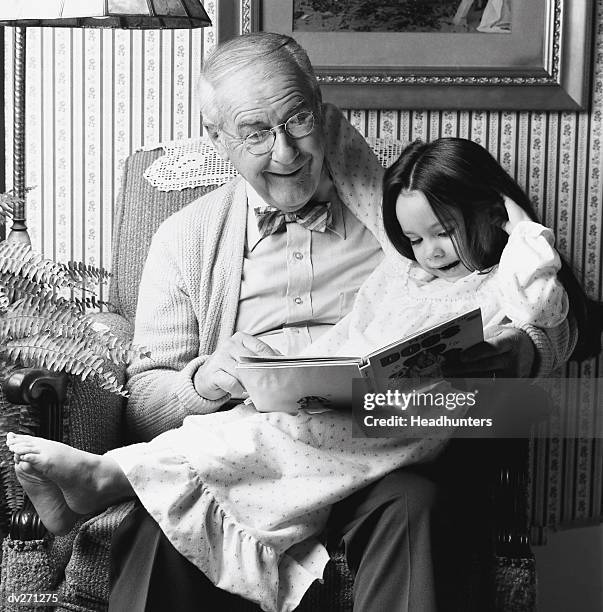 grandfather reading to child - headhunters stock-fotos und bilder