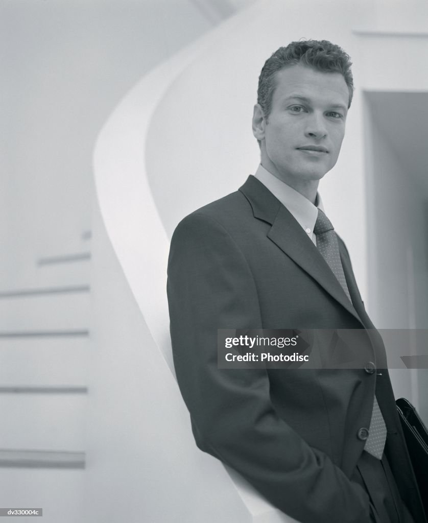 Businessman standing next to spiral staircase