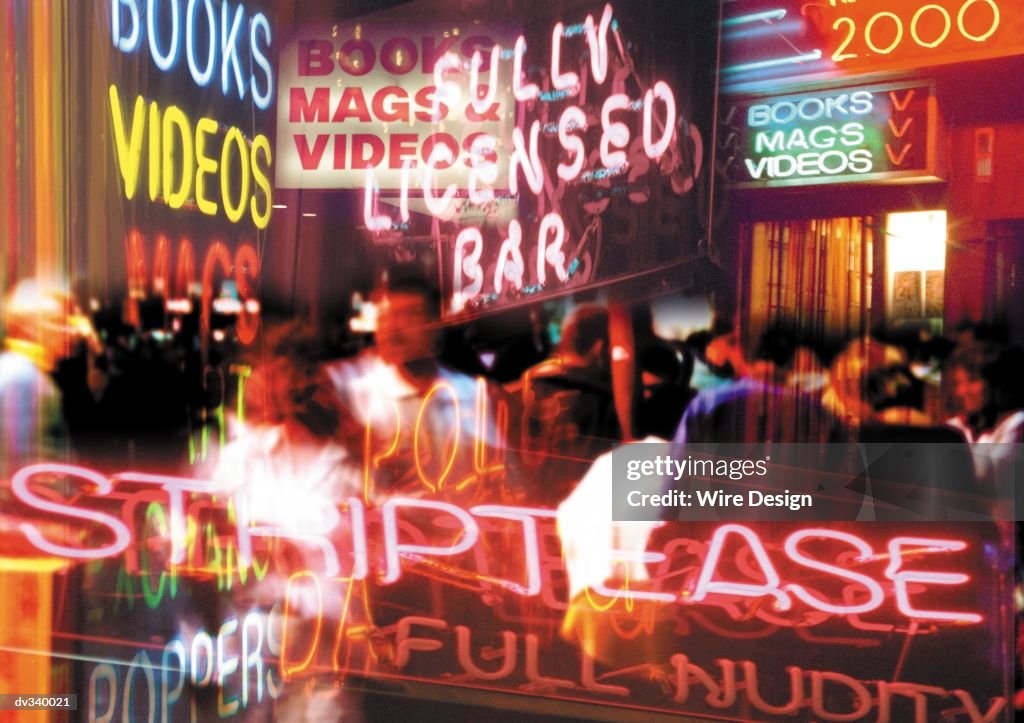 Neon signs advertising adult entertainment superimposed on crowd